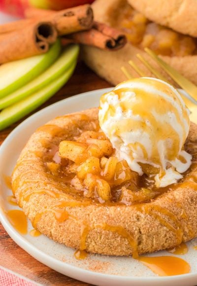 Apple pie cookie on a plate with a scoop of vanilla ice cream on top.