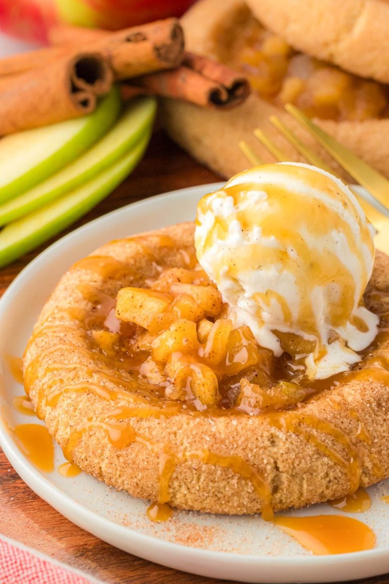 Apple pie cookie on a plate with a scoop of vanilla ice cream on top.