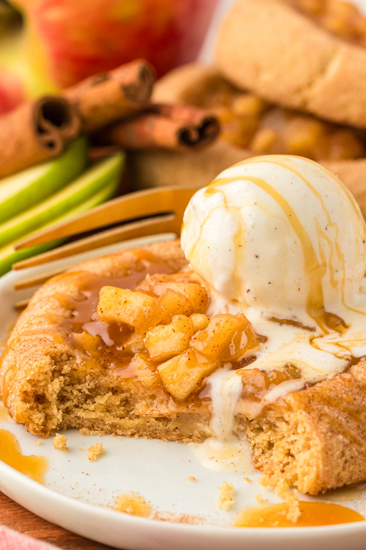 An apple pie cookie with a bite missing on a white plate.