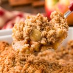 A serving spoon with a scoop of apple crisp from the pan.