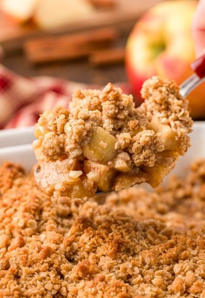 A serving spoon with a scoop of apple crisp from the pan.