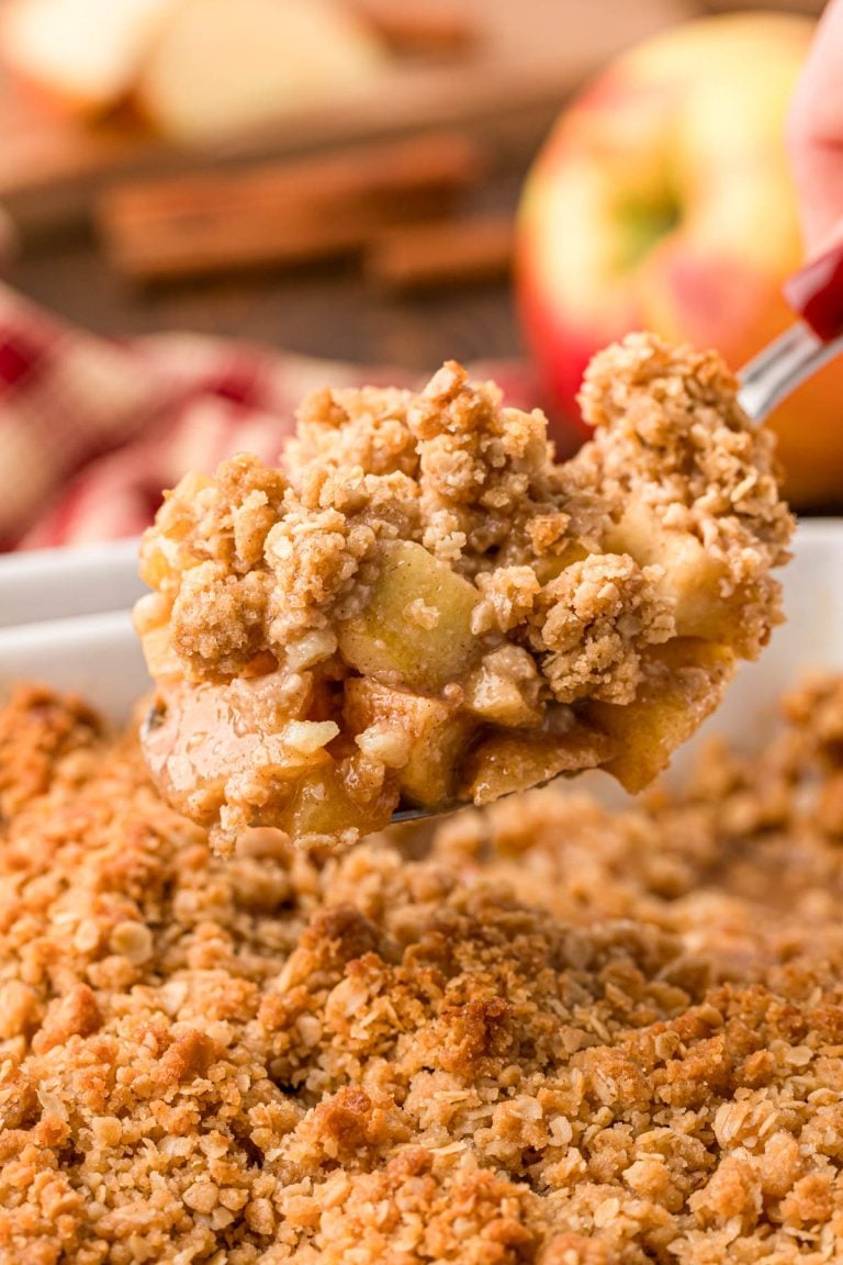 A serving spoon with a scoop of apple crisp from the pan.
