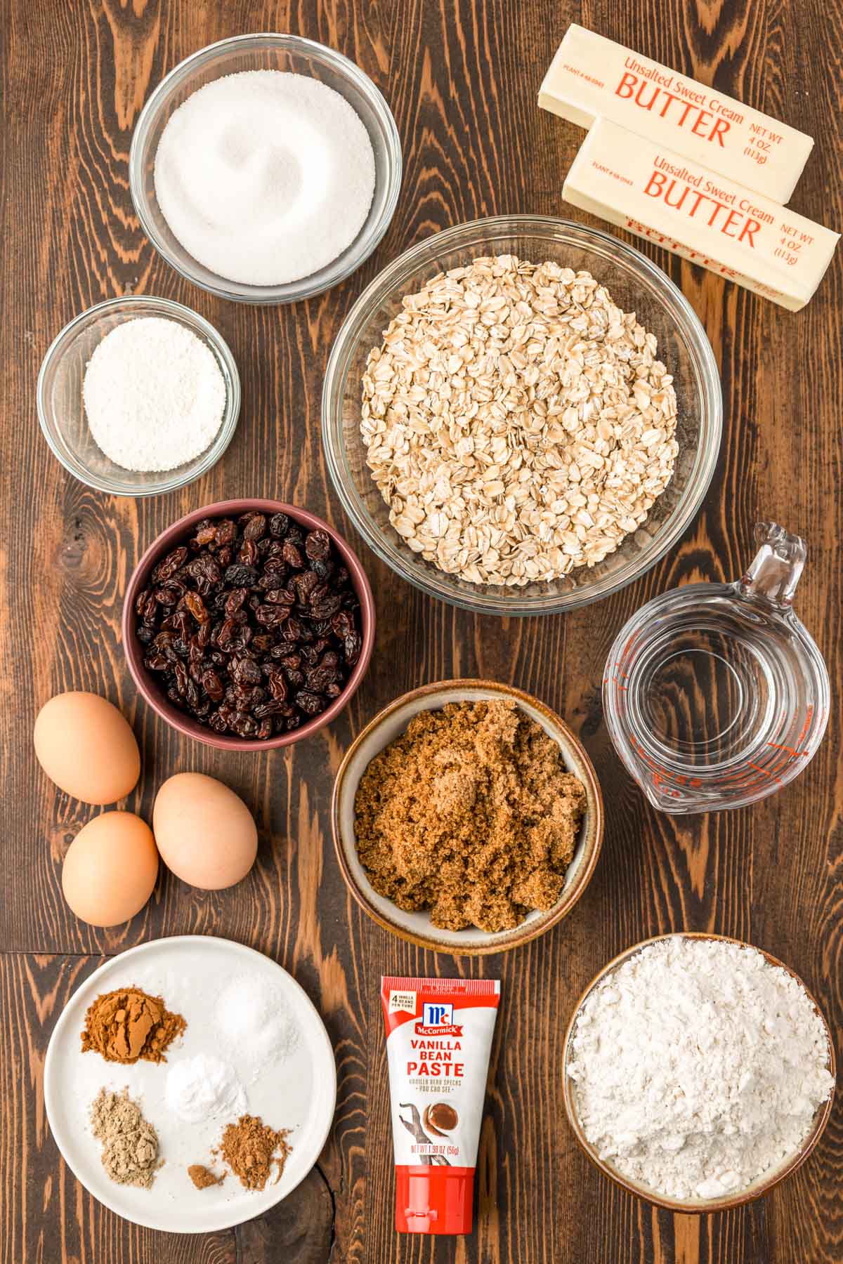 Ingredients to make oatmeal raisin cookies on a wooden table.