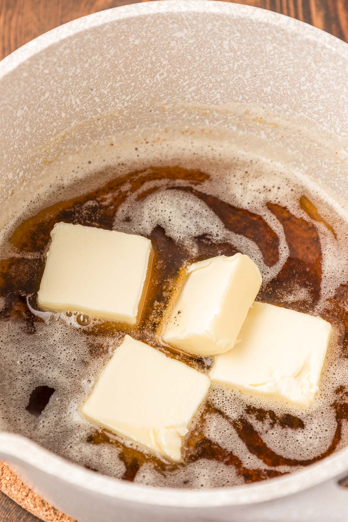 Butter pieces being added to a pan with browned butter.