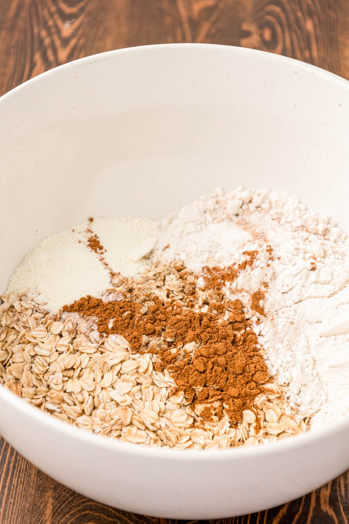 Dry ingredients for oatmeal cookies in a white bowl.