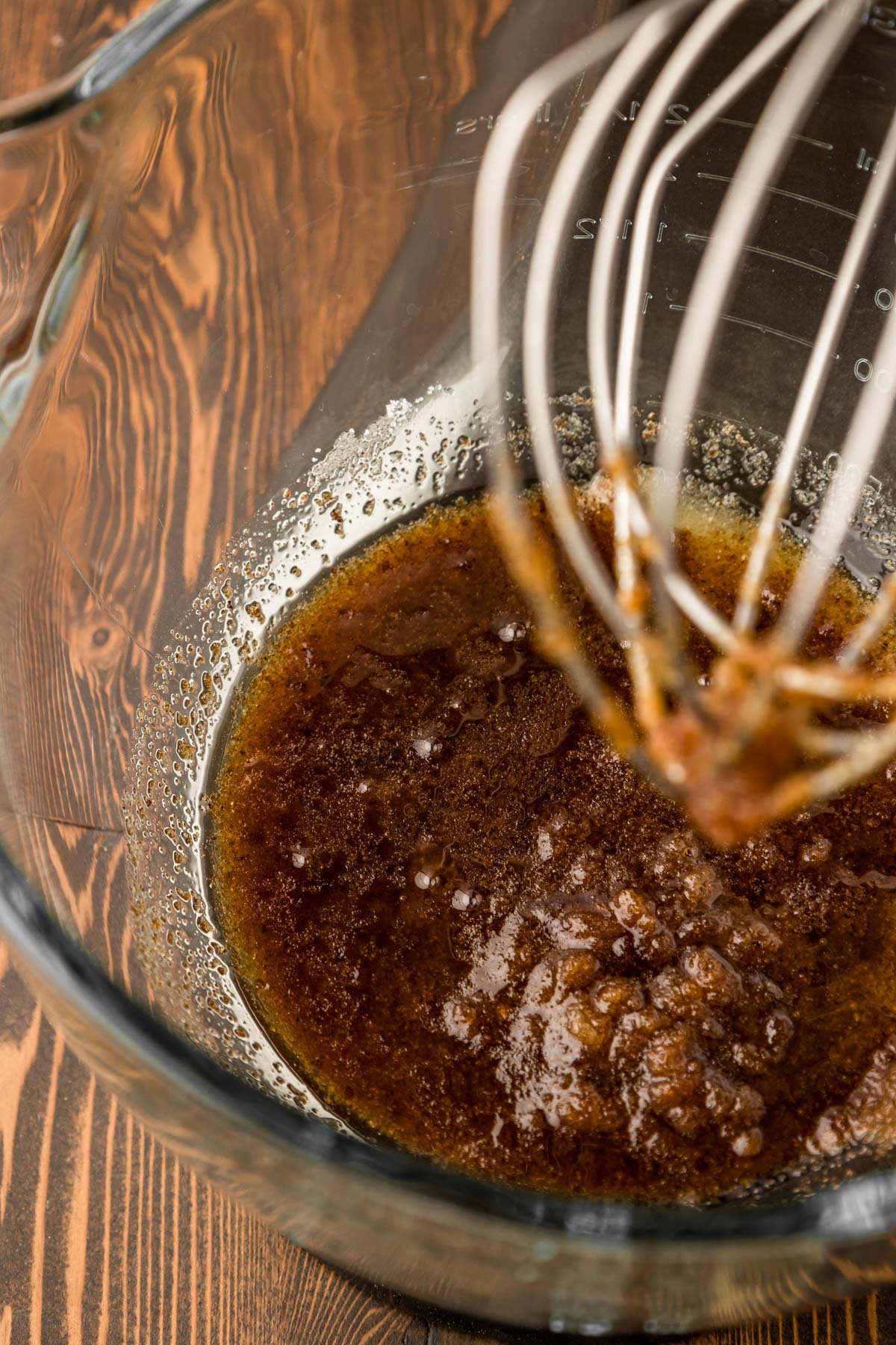 Sugar and browned butter beaten together in a glass mixing bowl.