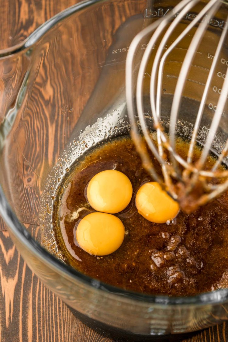 Egg yolks being added to butter and sugar in a bowl.
