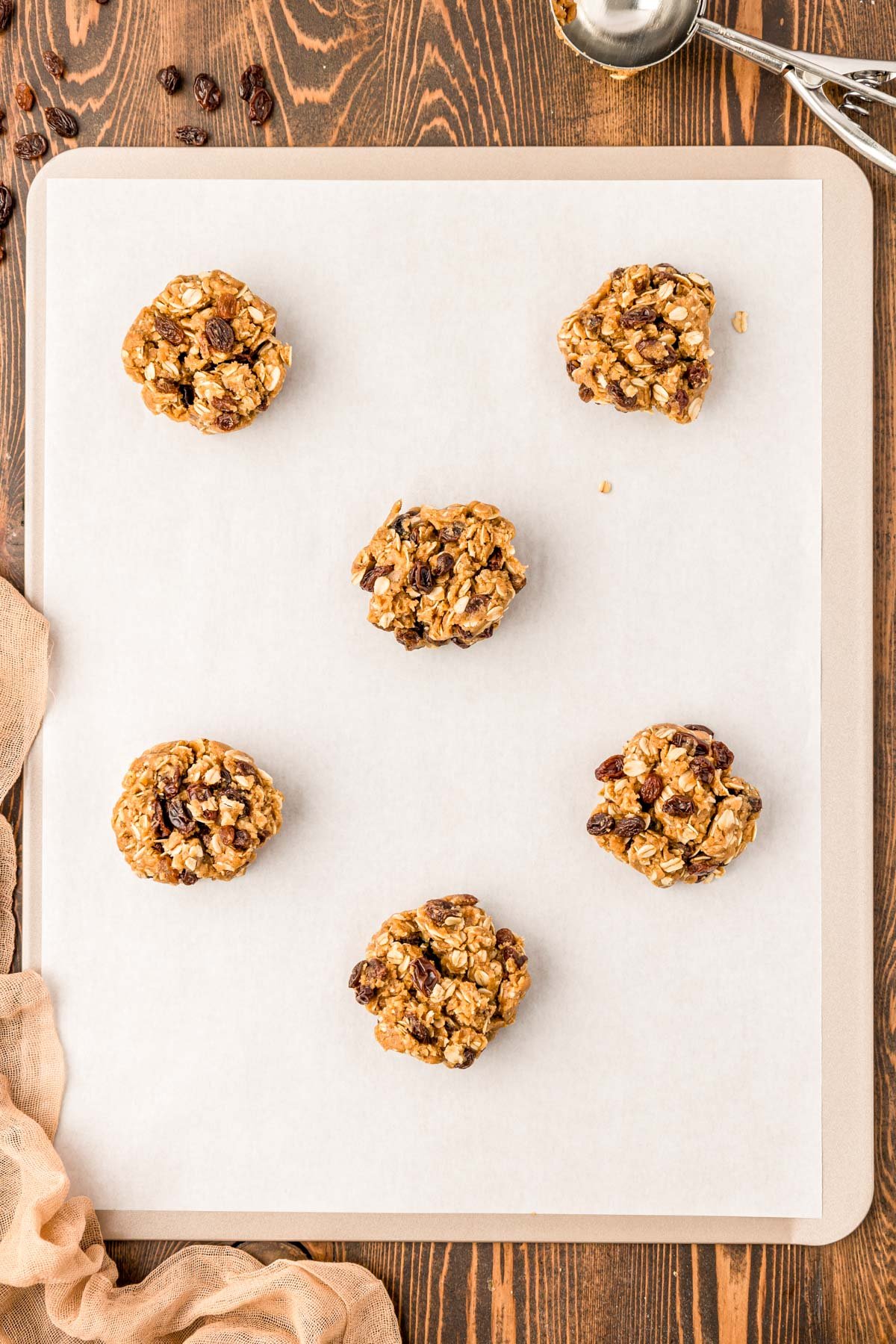 Oatmeal raisin cookie dough on a parchment lined baking sheet.