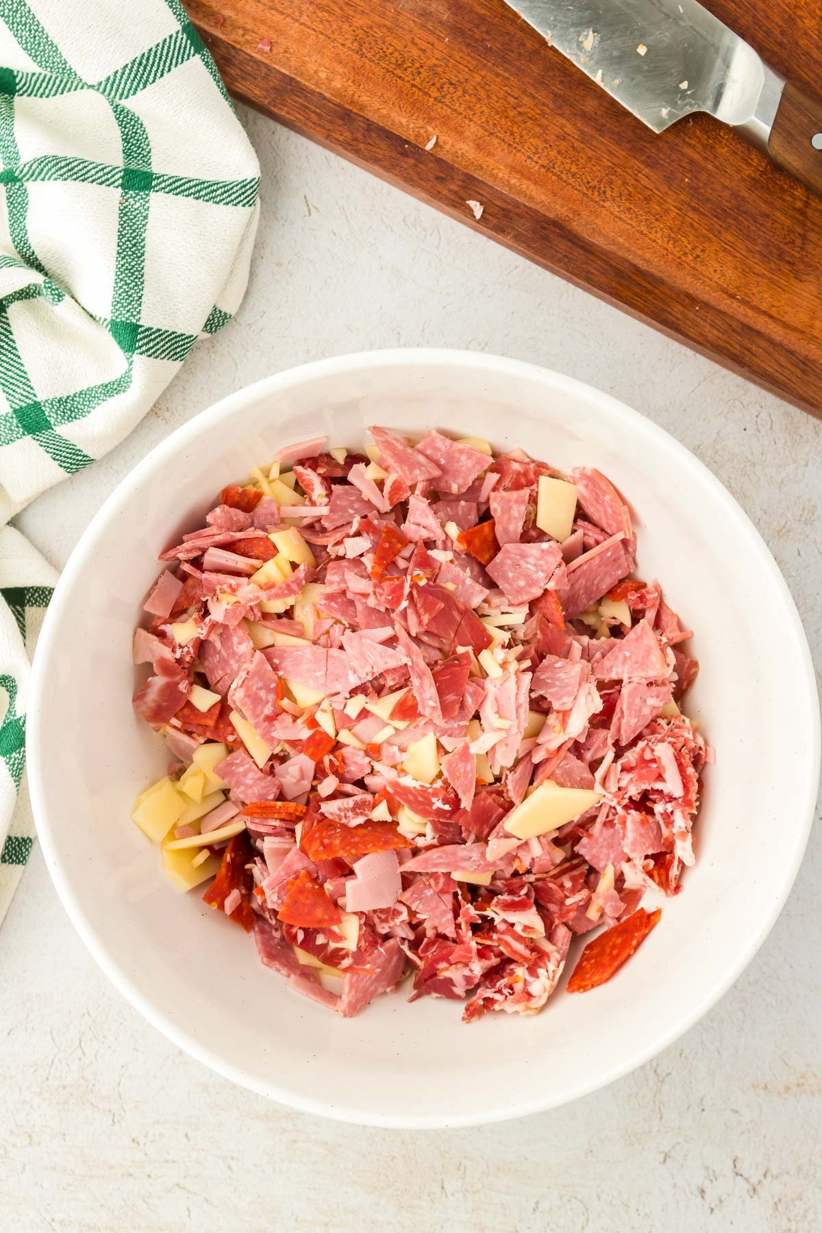 Chopped deli meat and cheese in a large bowl.