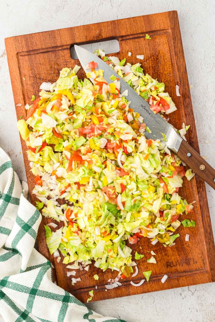 Chopped veggies and deli meat on a cutting board.