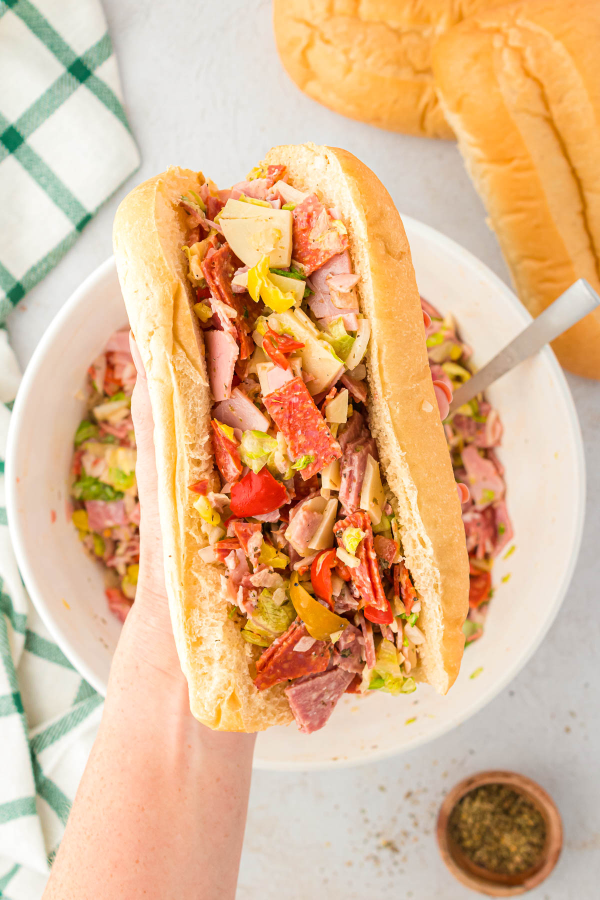 A woman's hand holding a chopped Italian sandwich.