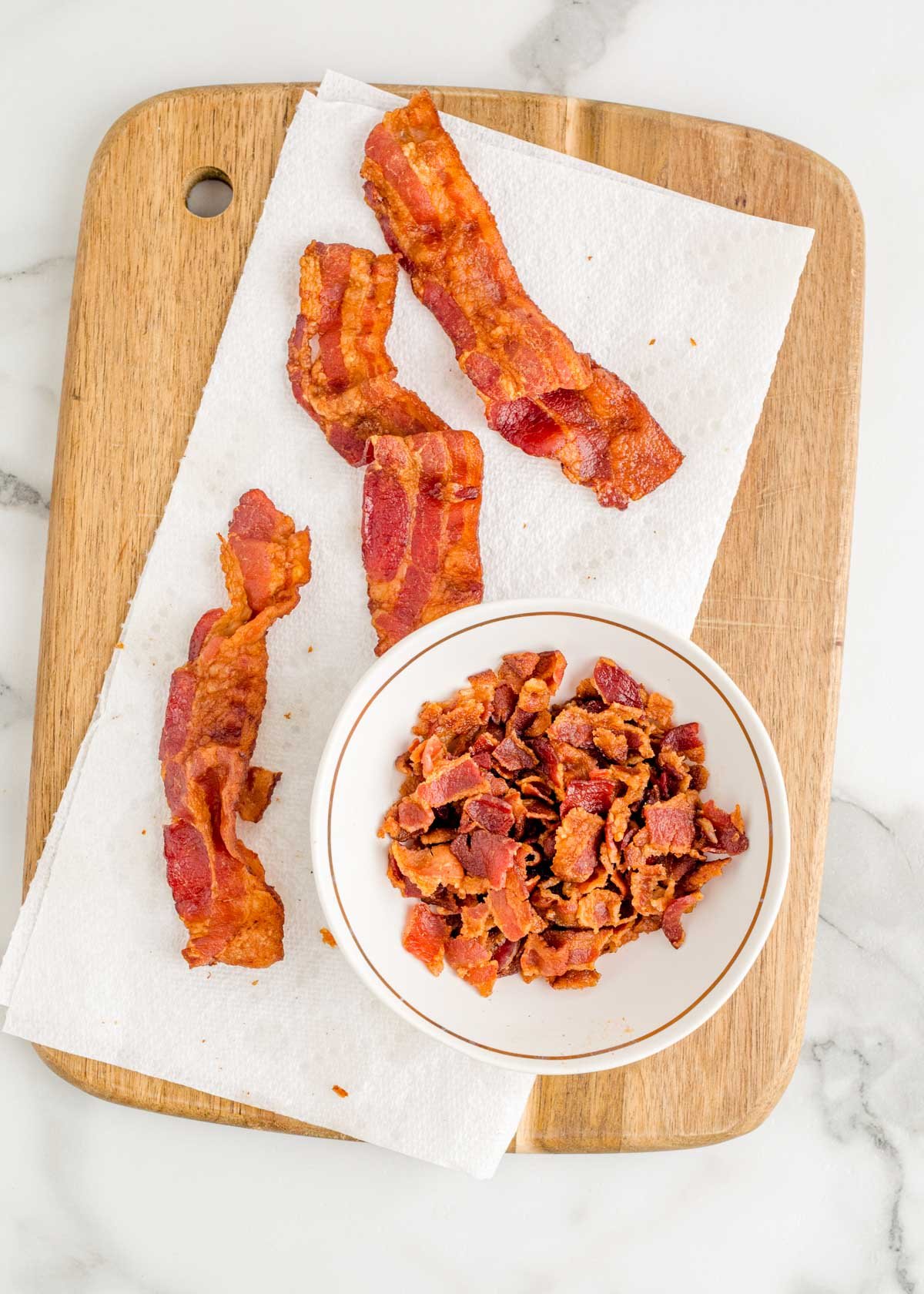 Bacon on a paper towel on a cutting board.