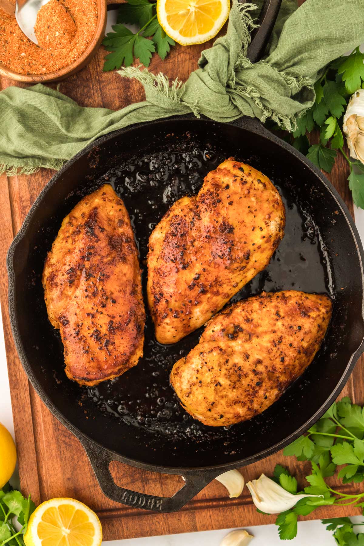 Overhead photo of three juicy chicken 101 chicken breasts in a cast iron skillet.