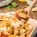 A wooden spoon scooping marry me chicken pasta out of a casserole dish.