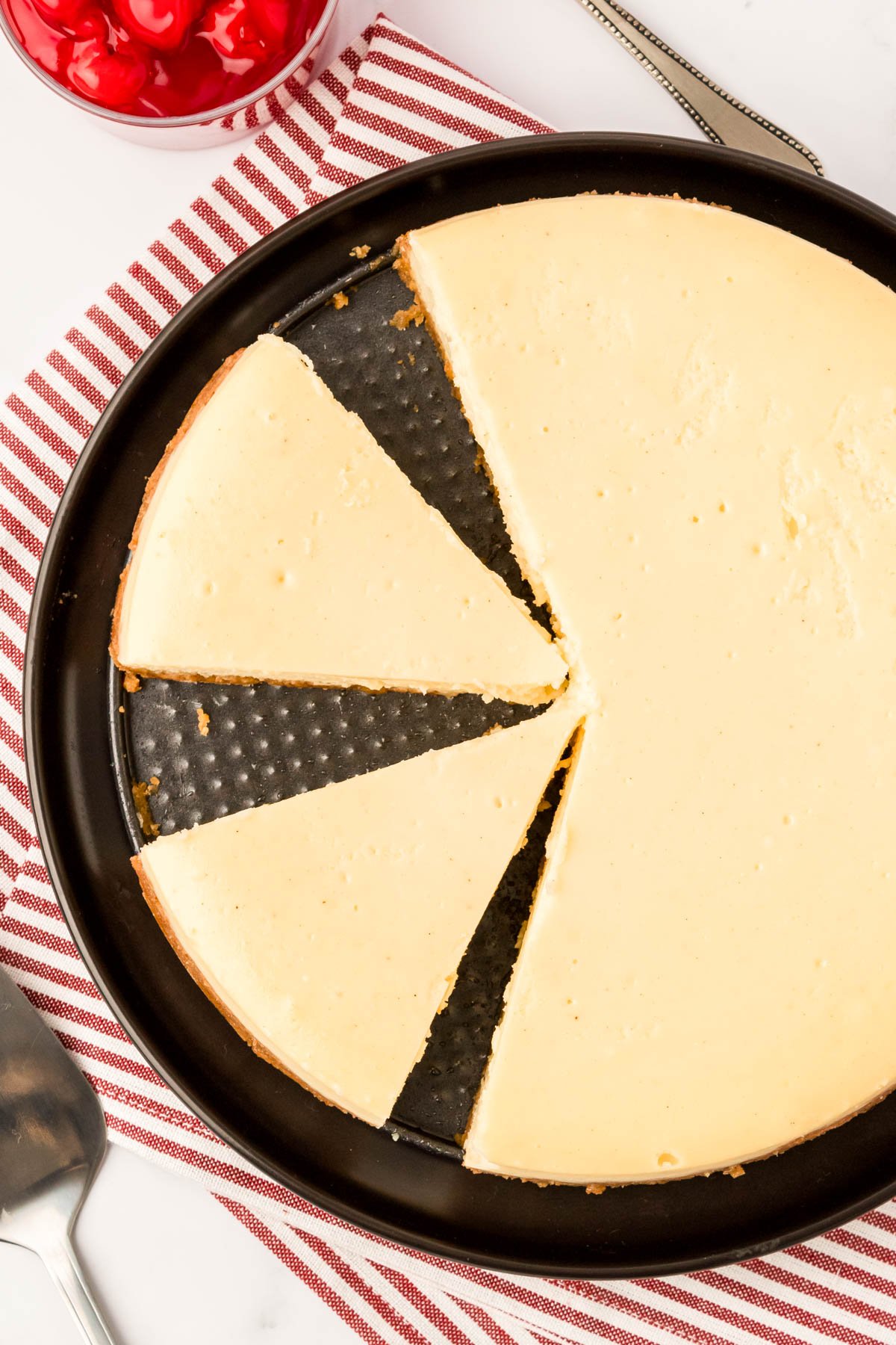 Overhead photo of a cheesecake with some slices cut and one missing.