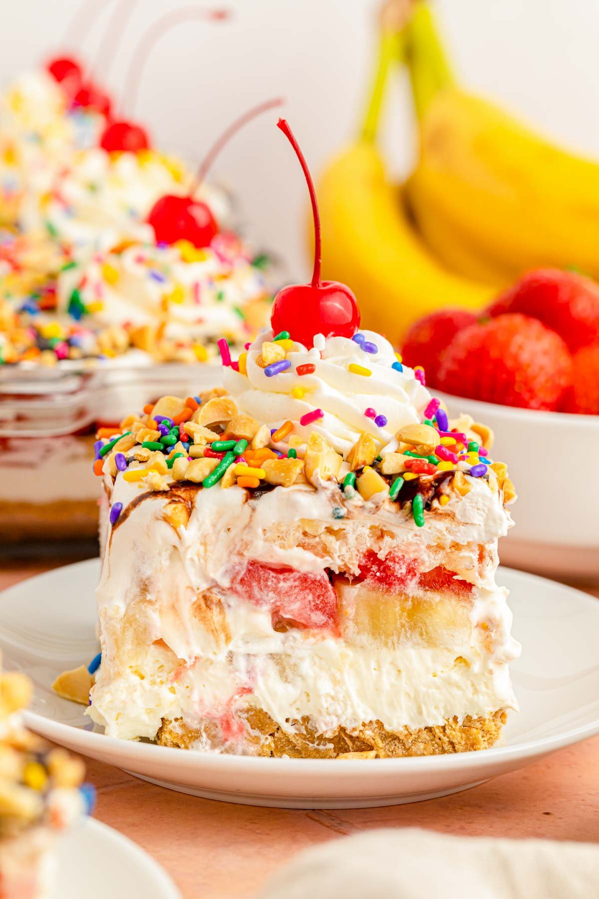 A slice of no bake banana split cheesecake on a white plate.