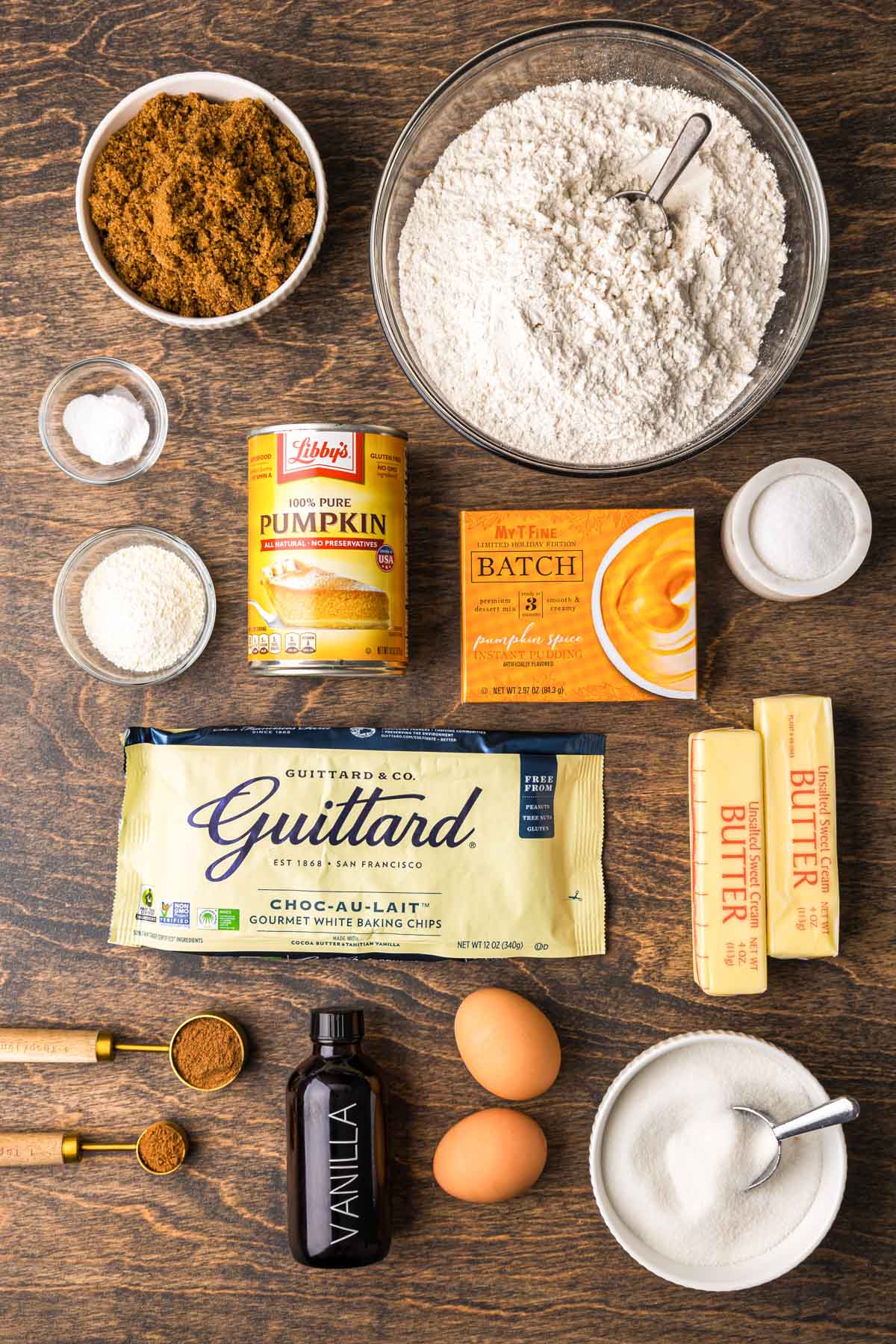 Ingredients to make pumpkin white chocolate chip cookies on a wooden table.