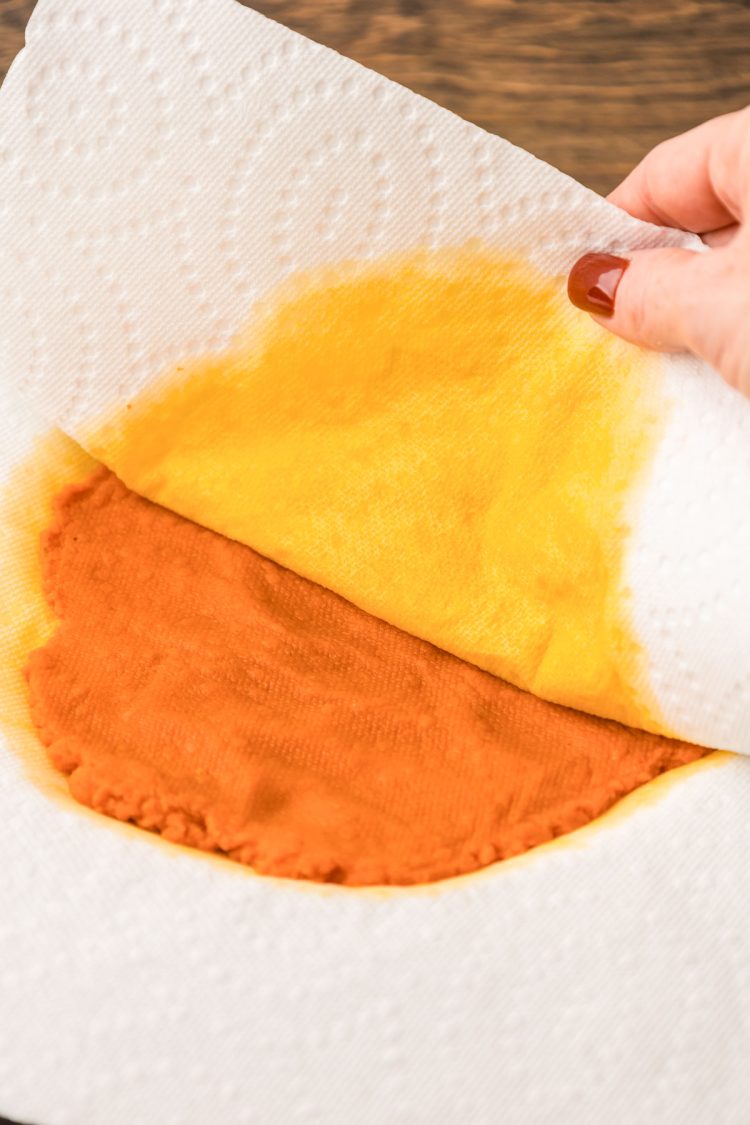 Paper towel pulling away from pumpkin puree that it soaked up moisture from.