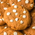 Close up photo of pumpkin white chocolate chip cookies in a pile.