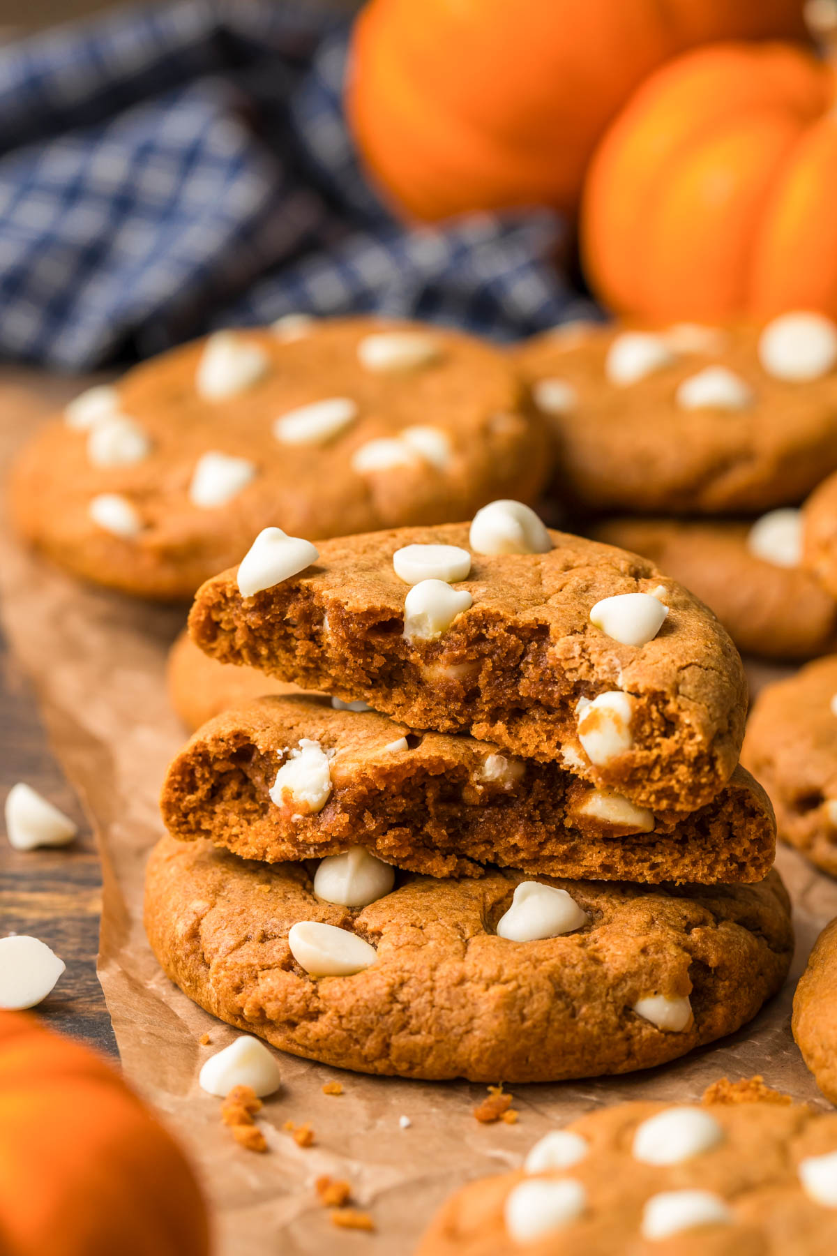 Pumpkin white chocolate cookies on a piece of parchment paper, the top cookies have been broken in half.