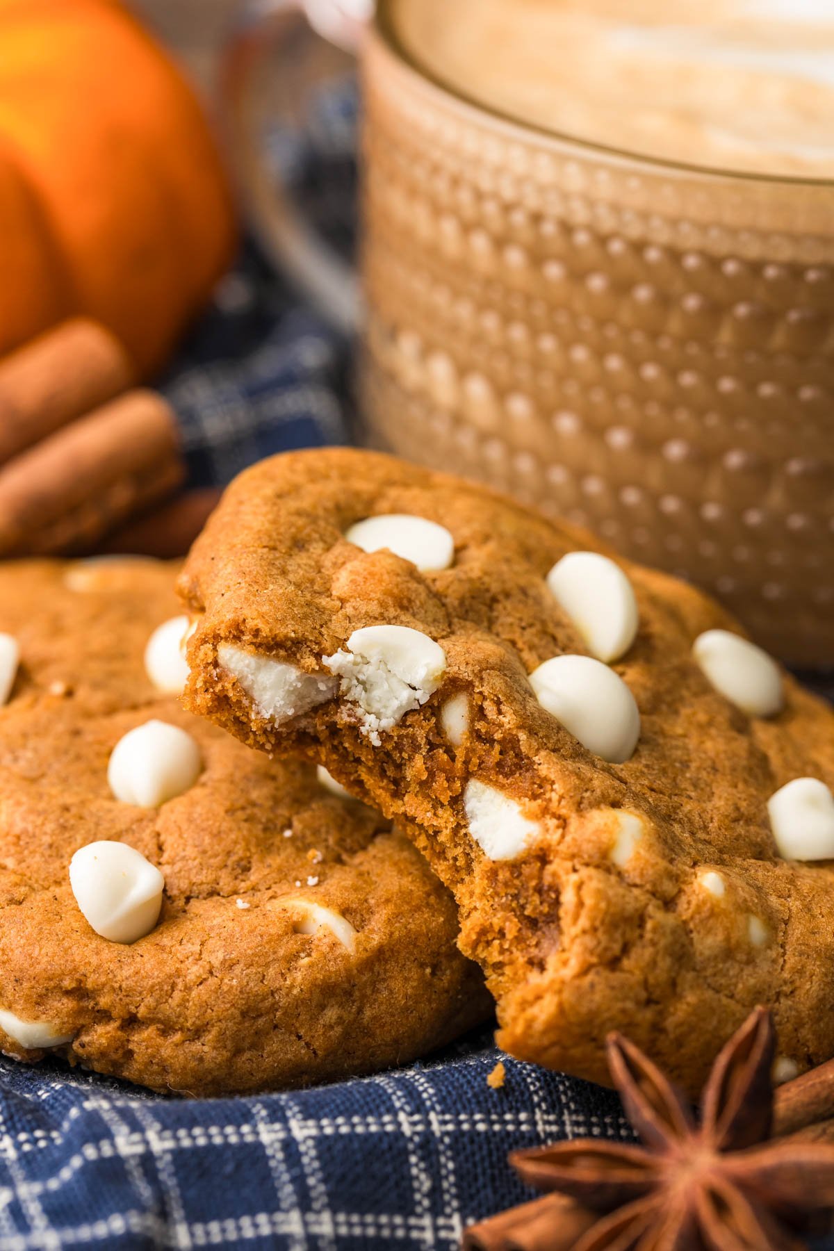 Pumpkin White Chocolate Chip cookies on a blue napkin with one missing a bite.