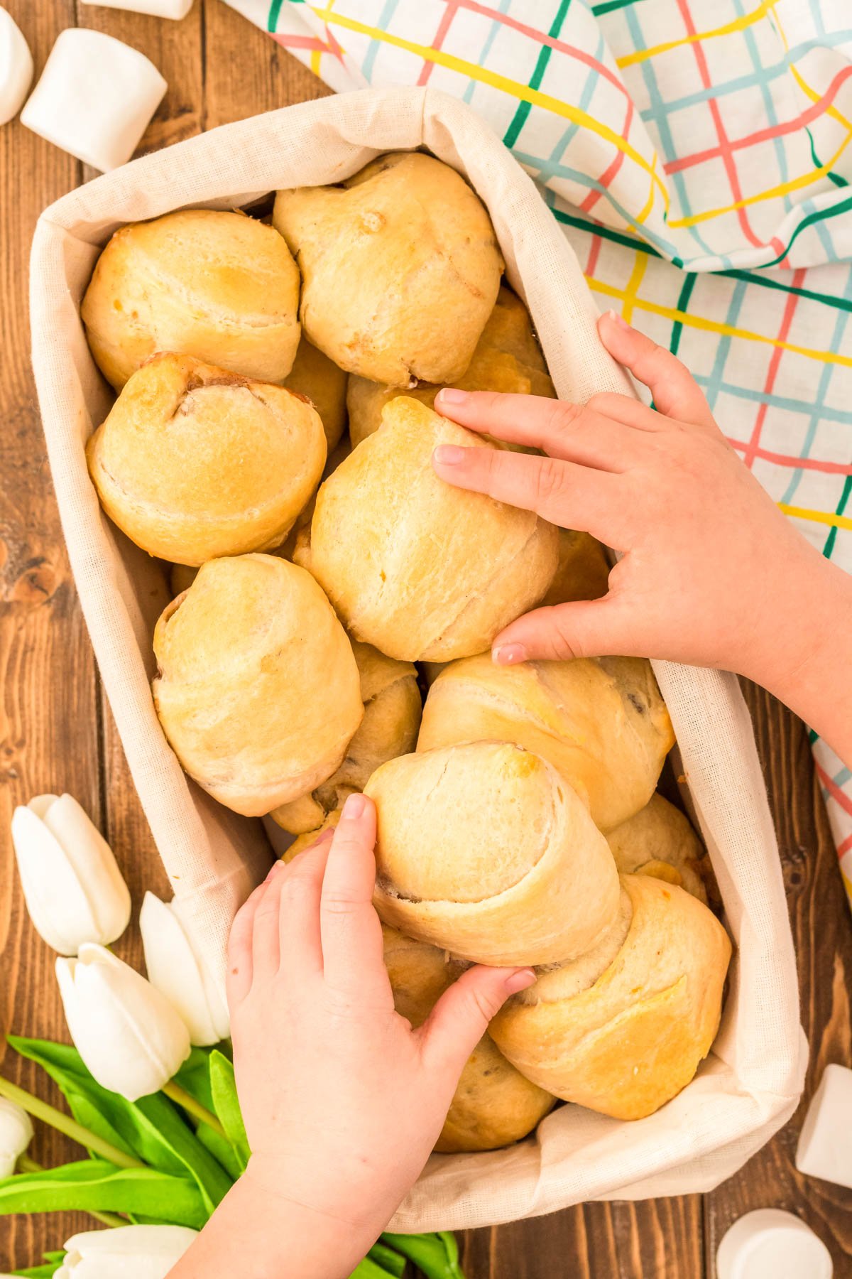 Toddler hands grabbing resurrection rolls out of a basket at Easter.