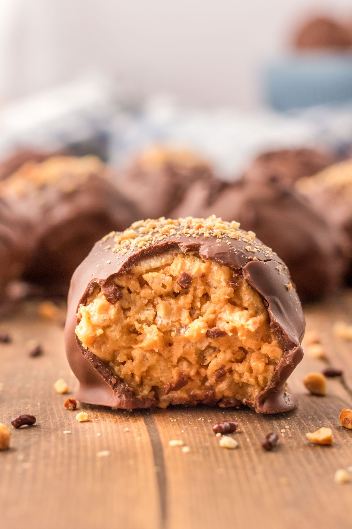 A peanut butter ball on a wooden table with a bite taken out of it.