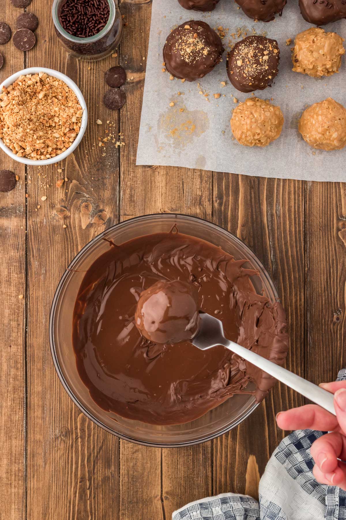 Peanut butter balls being dipped in melted chocolate.