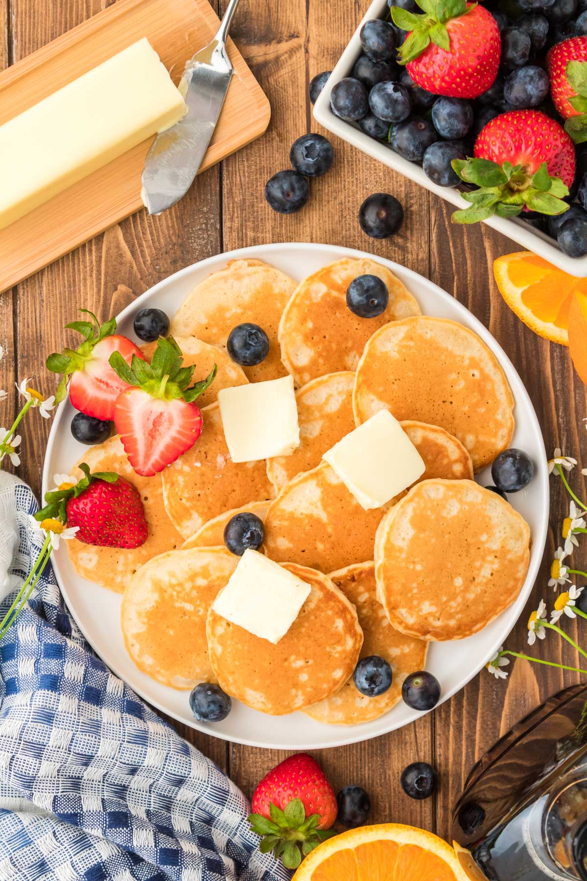 Overhead photo of a plate of silver dollar pancakes with butter and berries.