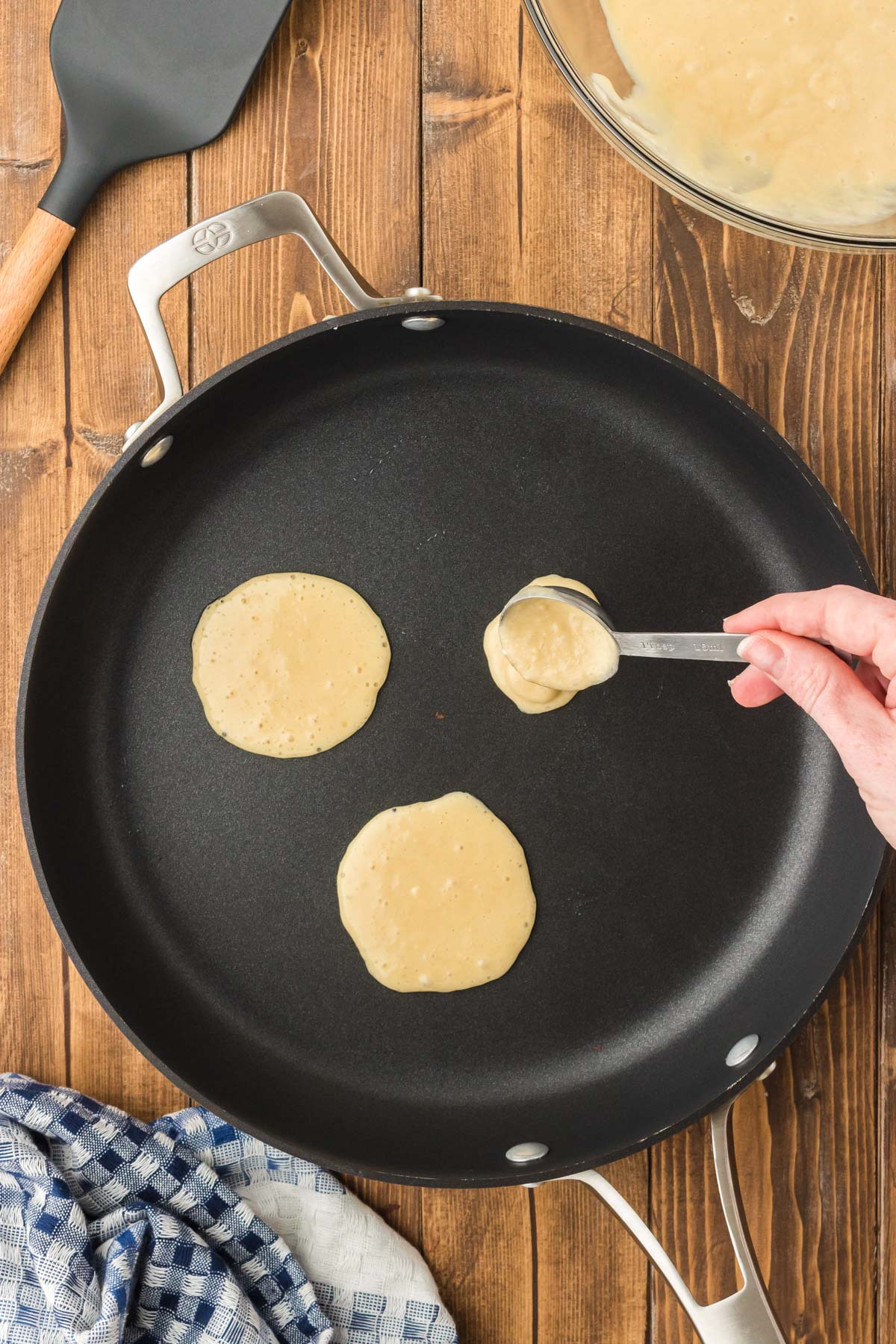 Pancake batter being spooned onto a skillet.