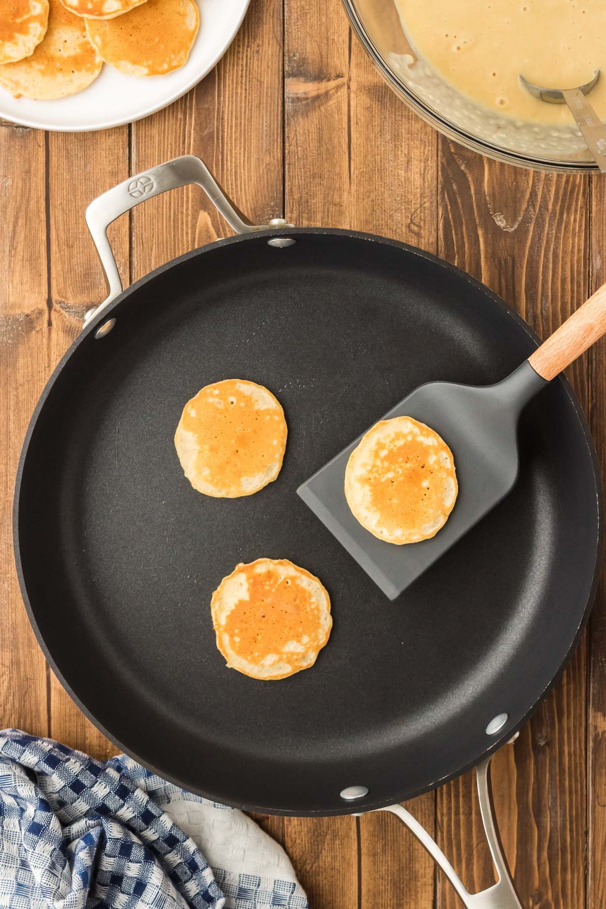 Mini pancakes being cooked on a pan.