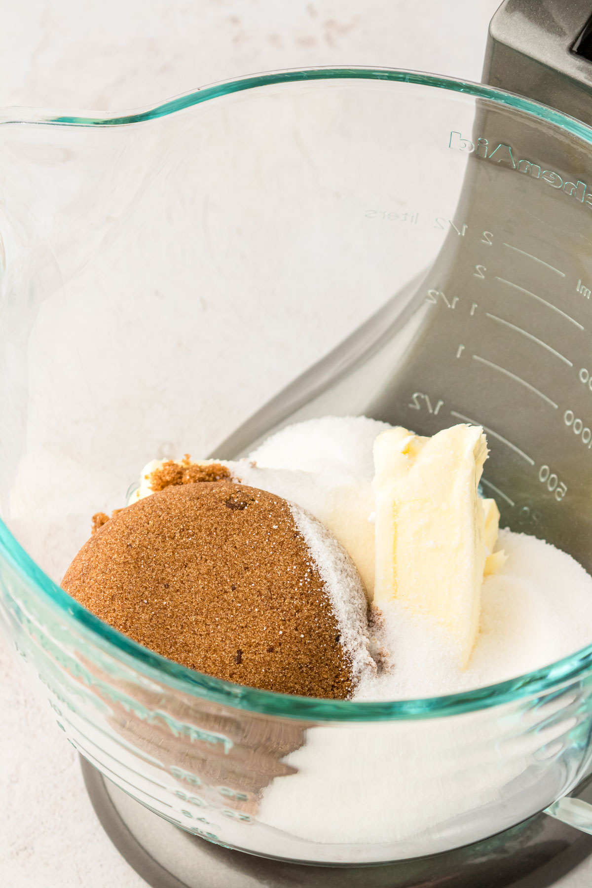 Sugar and butter in a glass stand mixer bowl ready to be mixed.