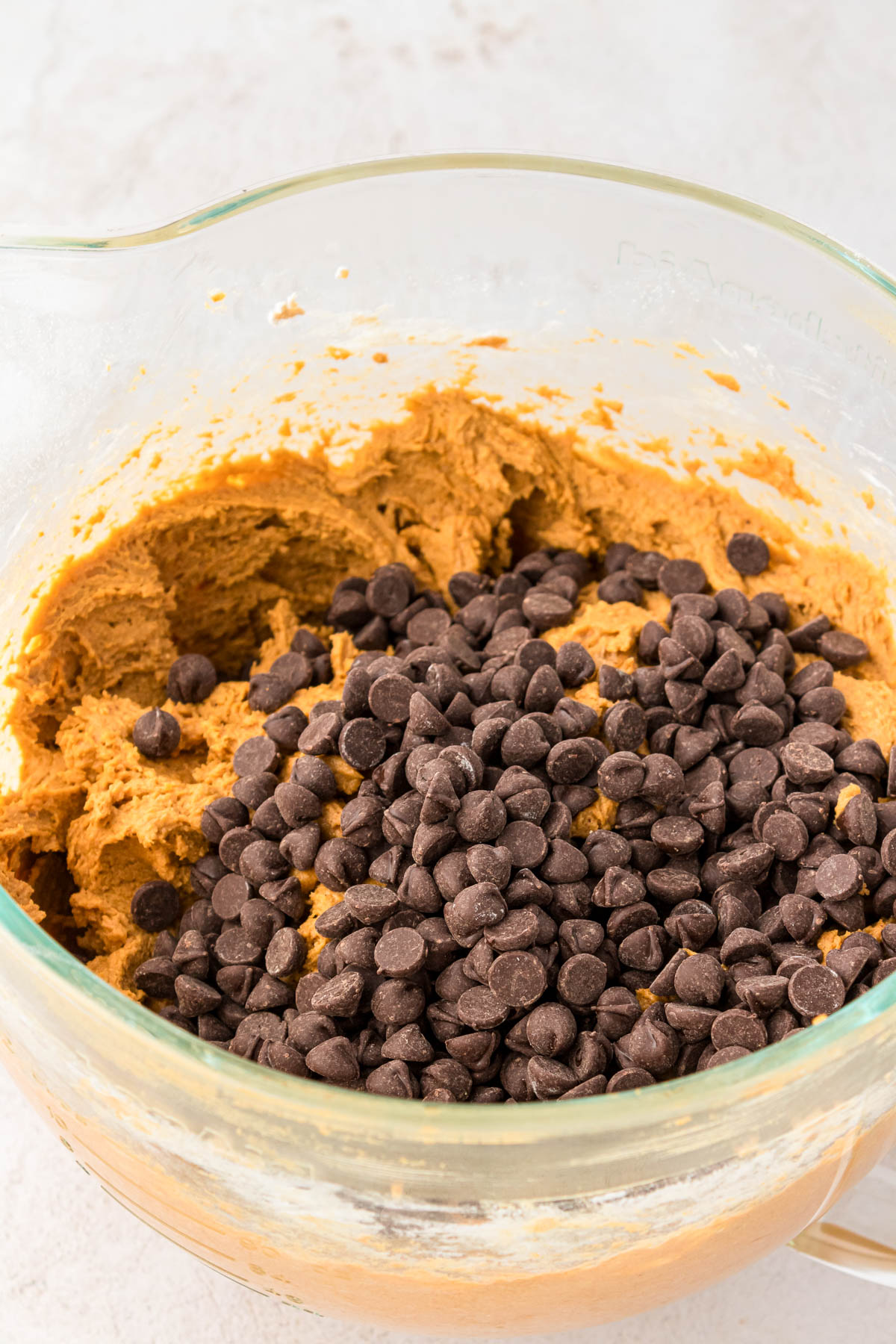 Chocolate chips being added to pumpkin cookie dough.