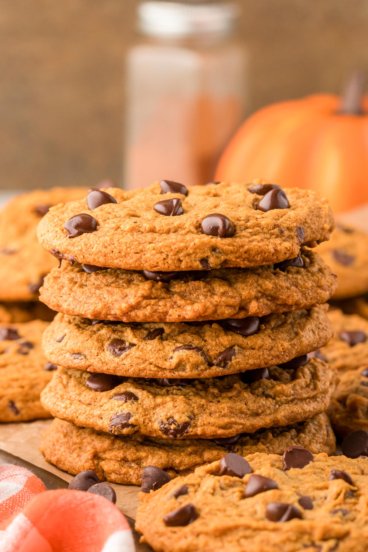 A stack of chewy pumpkin chocolate chip cookies on a table.