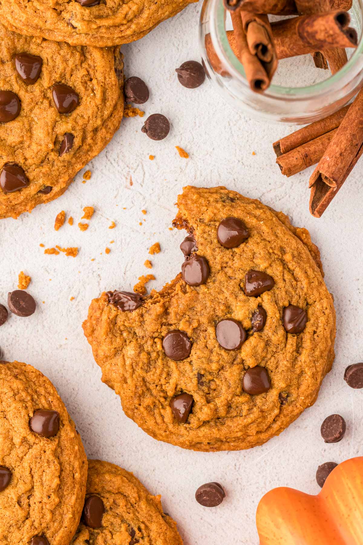 Pumpkin chocolate chip cookies on a counter, one is missing a bite.