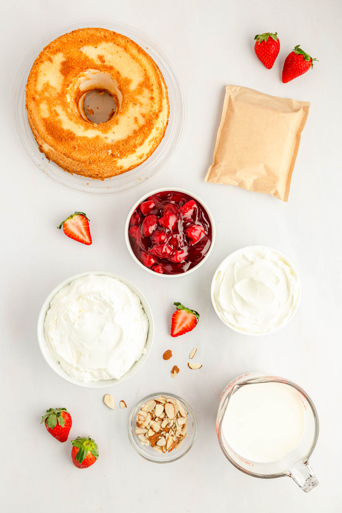 Ingredients to make strawberry heaven on earth cake on a white counter.