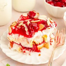 Close up of a slice of Heaven on Earth Cake made with strawberries on a white plate with a fork.