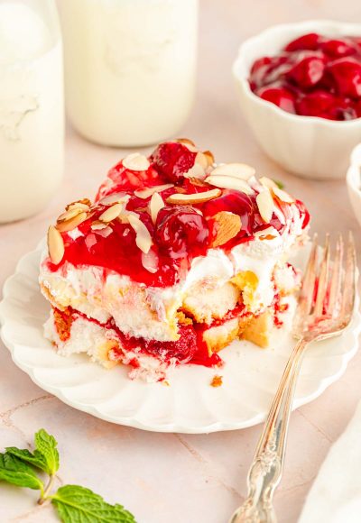 Close up of a slice of Heaven on Earth Cake made with strawberries on a white plate with a fork.