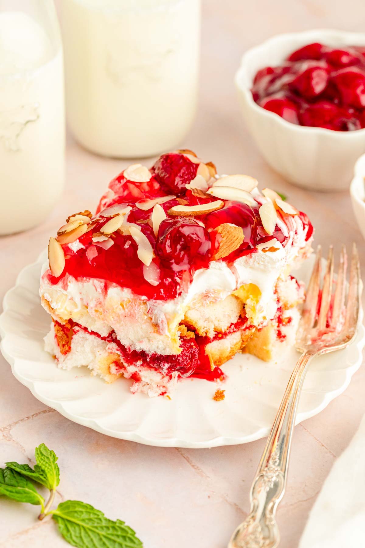 Close up of a slice of Heaven on Earth Cake made with strawberries on a white plate with a fork.