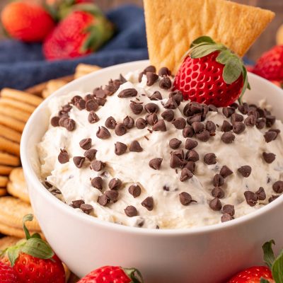 Close up of booty dip in a white bowl with fruit and cookies around it for dipping.