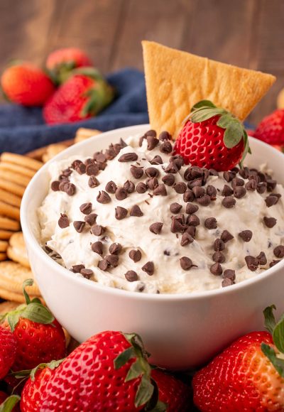 Close up of booty dip in a white bowl with fruit and cookies around it for dipping.