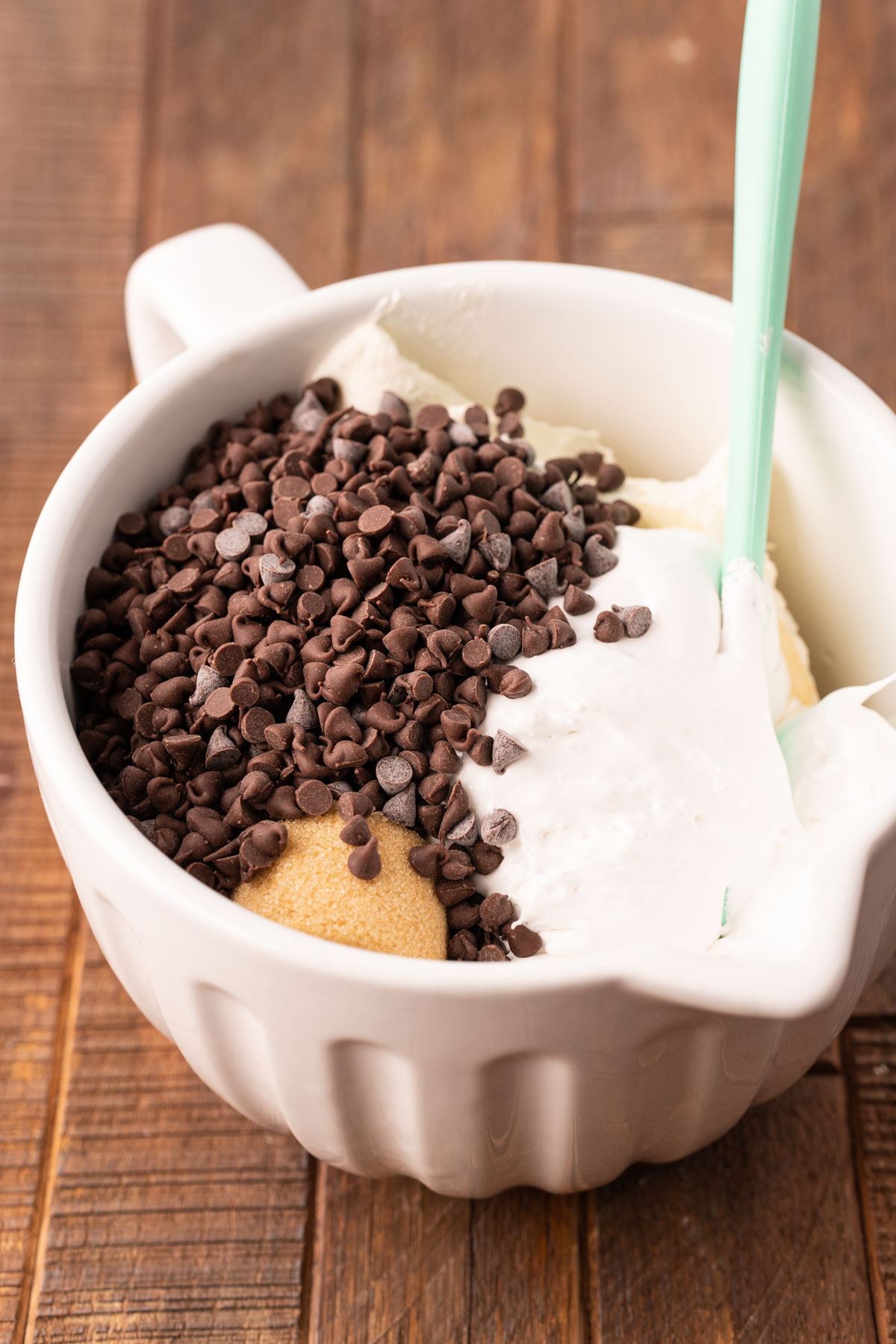 Ingredients to make booty dip in a white mixing bowl with a blue rubber spatula.