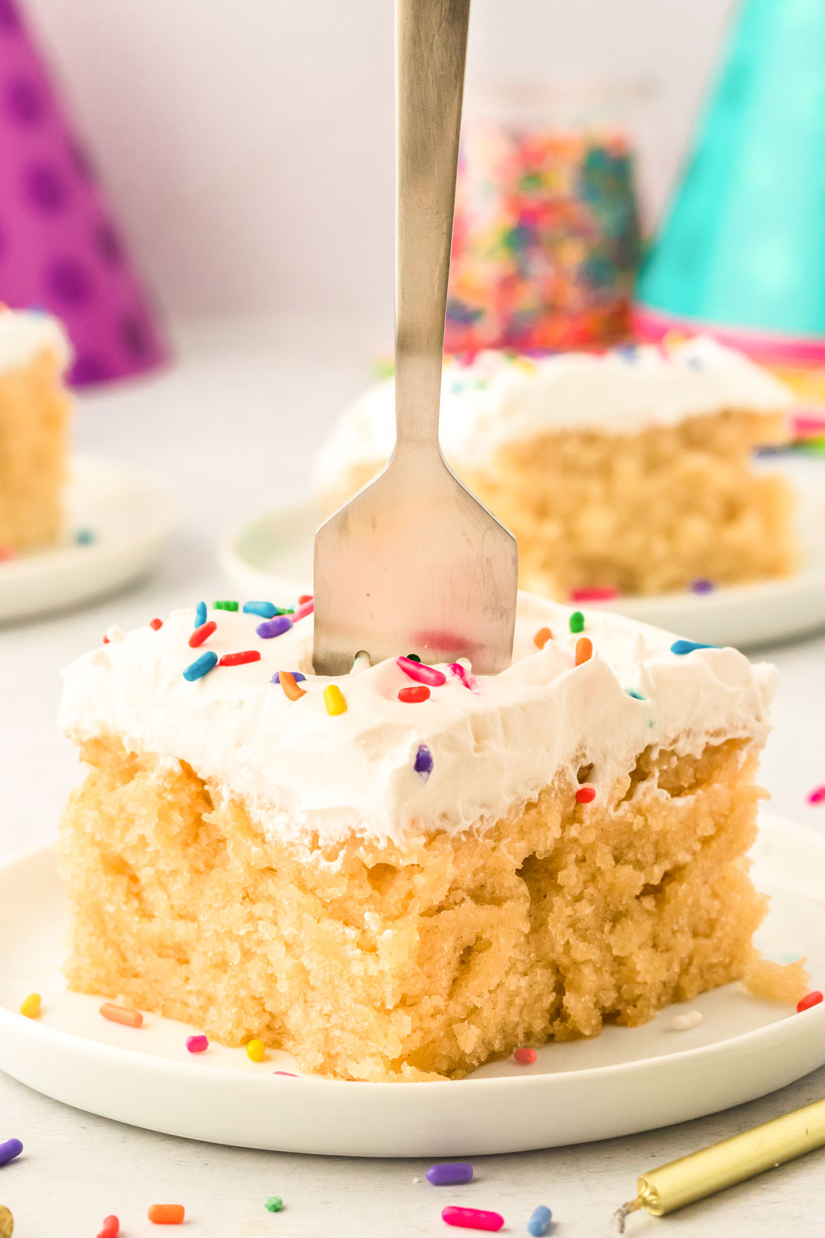 A fork digging into a slice of vanilla crazy cake on a white plate.