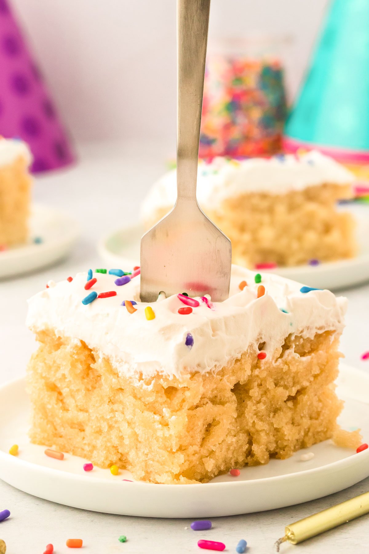 A fork digging into a slice of vanilla crazy cake on a white plate.