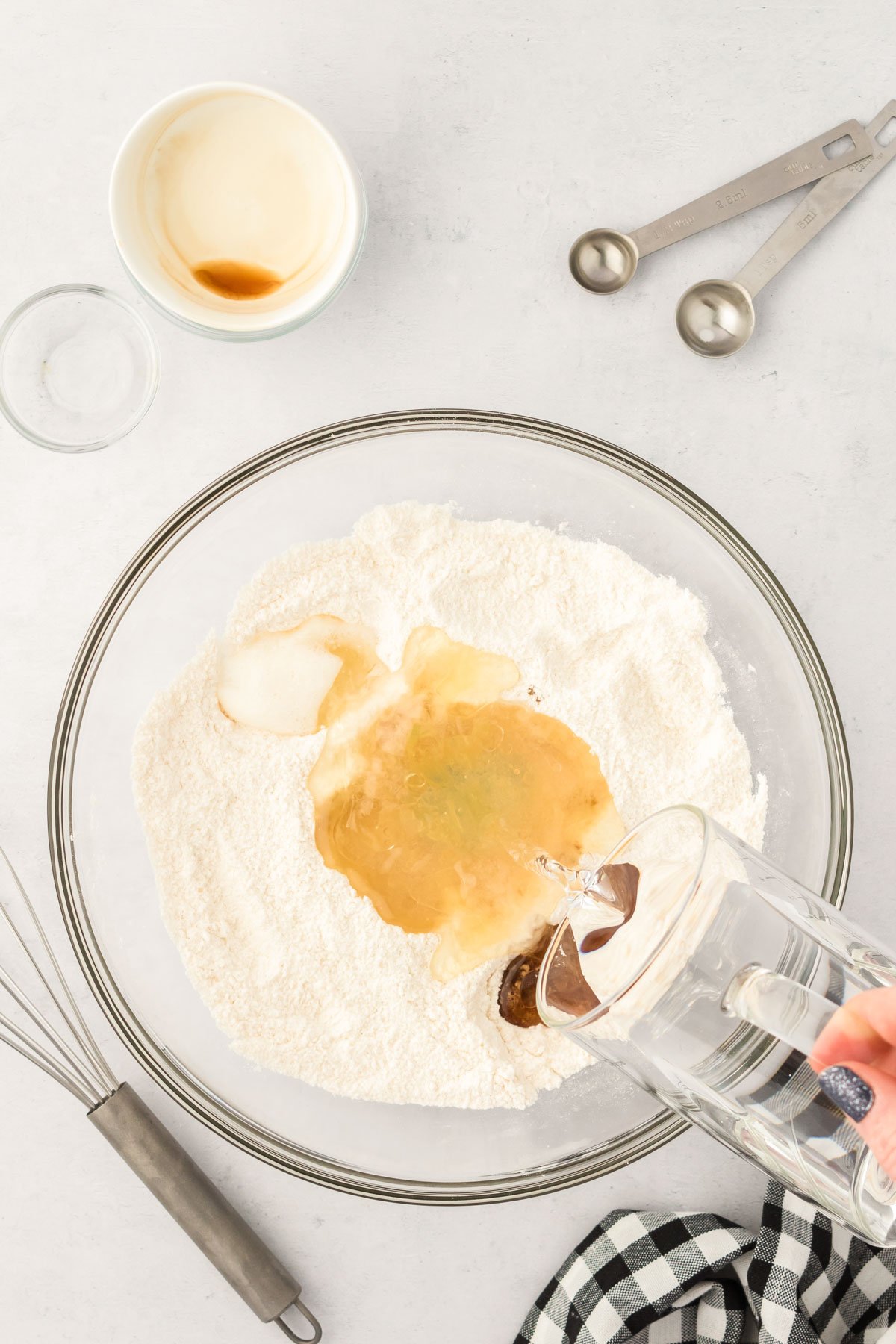 Water being poured over the top of a bowl of ingredients to make cake.