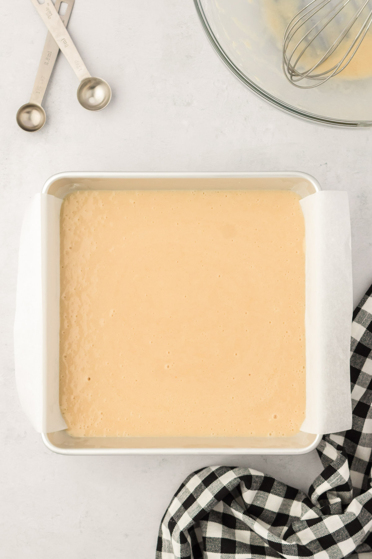Cake batter in a square parchment lined pan.