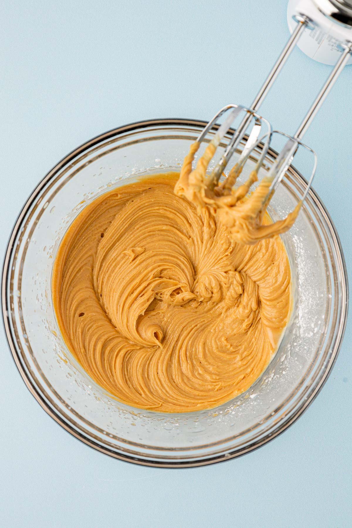 Butter, peanut butter, and other ingredients creamed together in a glass bowl.