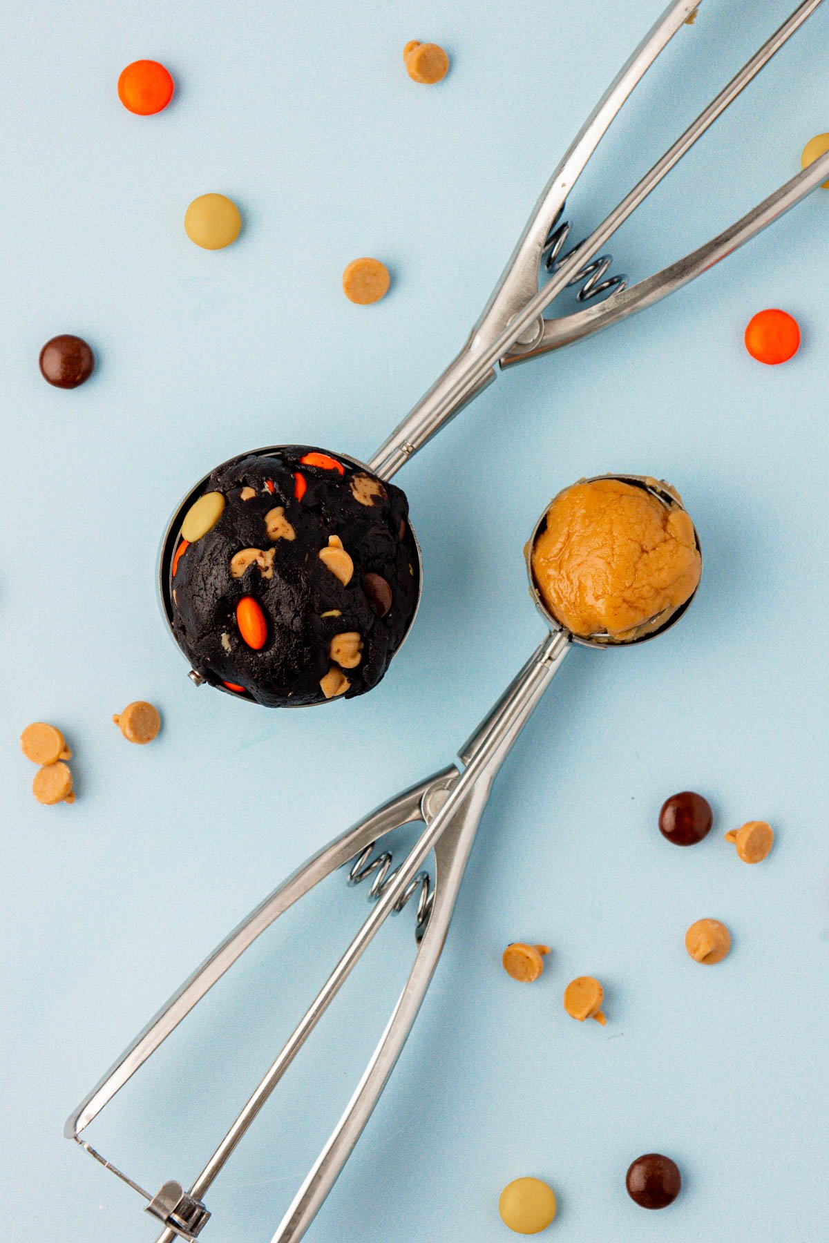 Cookie scoops on a blue surface with cookie dough and peanut butter filling in them.