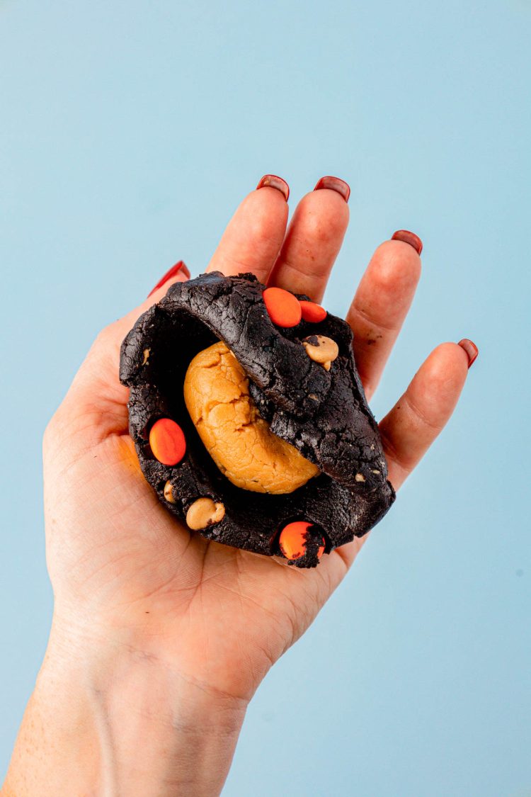 Peanut butter filling being enclosed in chocolate cookie dough.