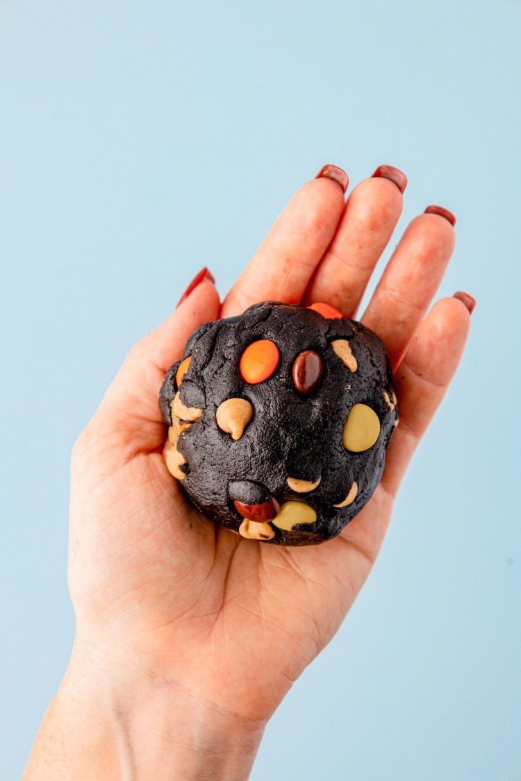 A ball of cookie dough in a woman's hand.